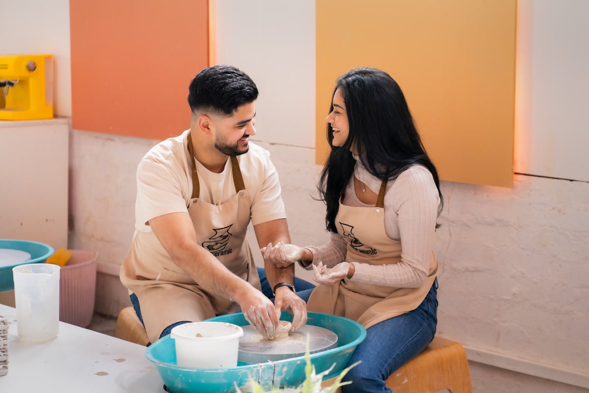 A couple laughing together at a pottery studio during their engagement session