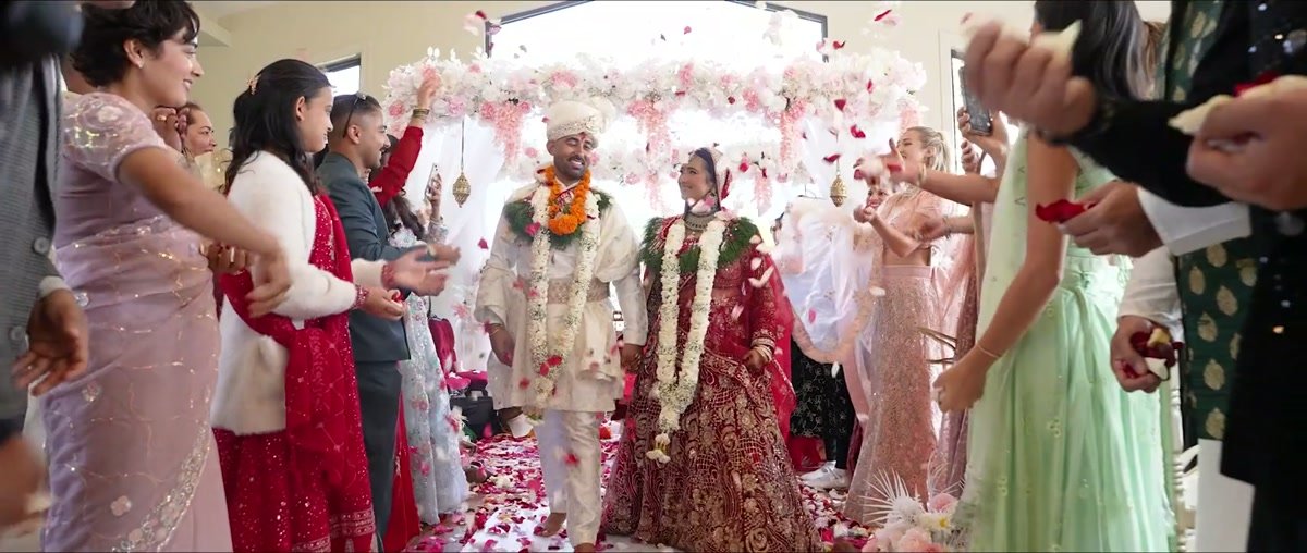 Guests throwing rose petals over a couple walking out of their ceremony